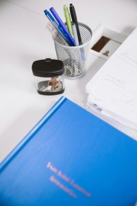 Clean desktop with a blue book, pen holder, and stationery, perfect for research and study.